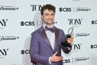 Daniel Radcliffe holding his Tony Award on stage | FAME DELIVERED